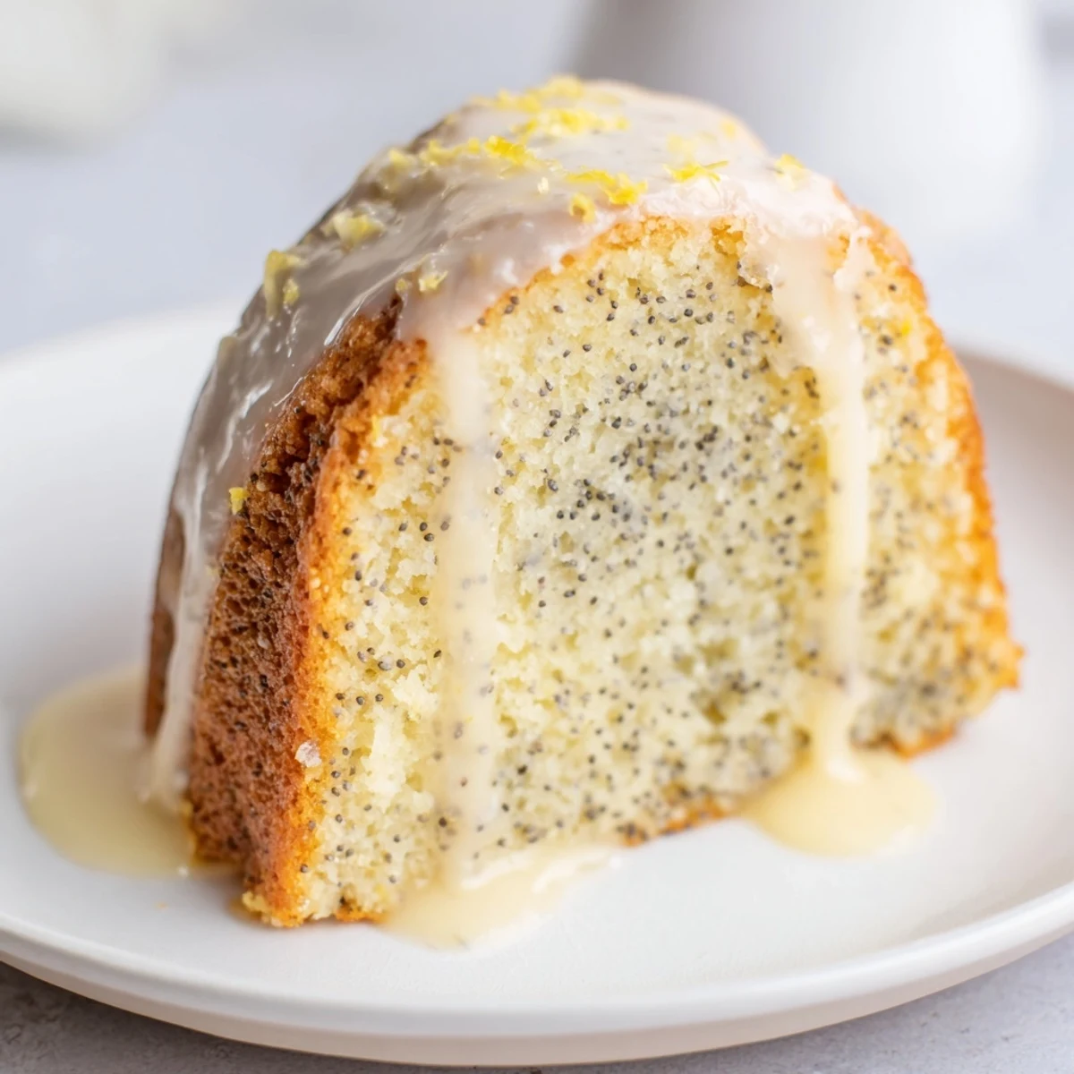 A slice of golden Lemon Poppy Seed Bundt Cake with a generous blanket of zesty glaze.