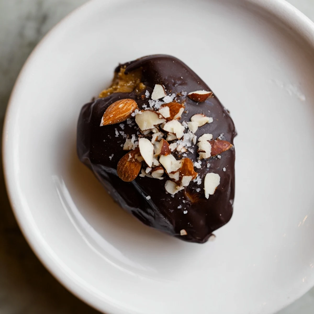 Decadent close-up shows glossy Chocolate Covered Dates, filled with almond butter, ready to enjoy.