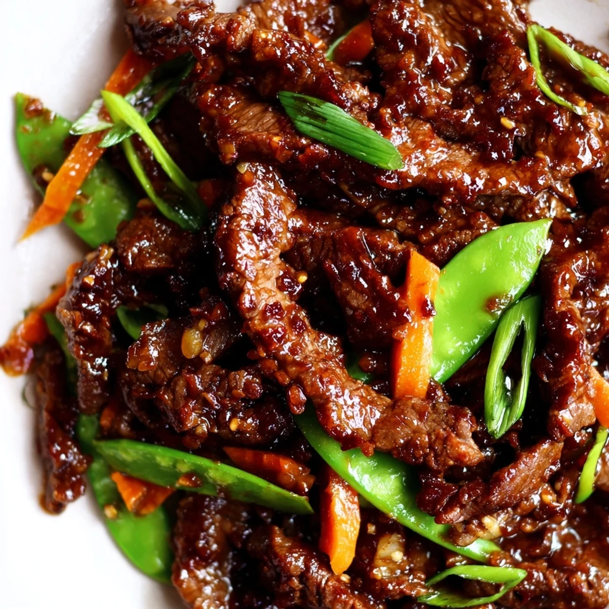 A sizzling wok filled with freshly cooked Beef Stir Fry with Snow Peas and Carrots, garnished with green onions and ready to serve over rice.