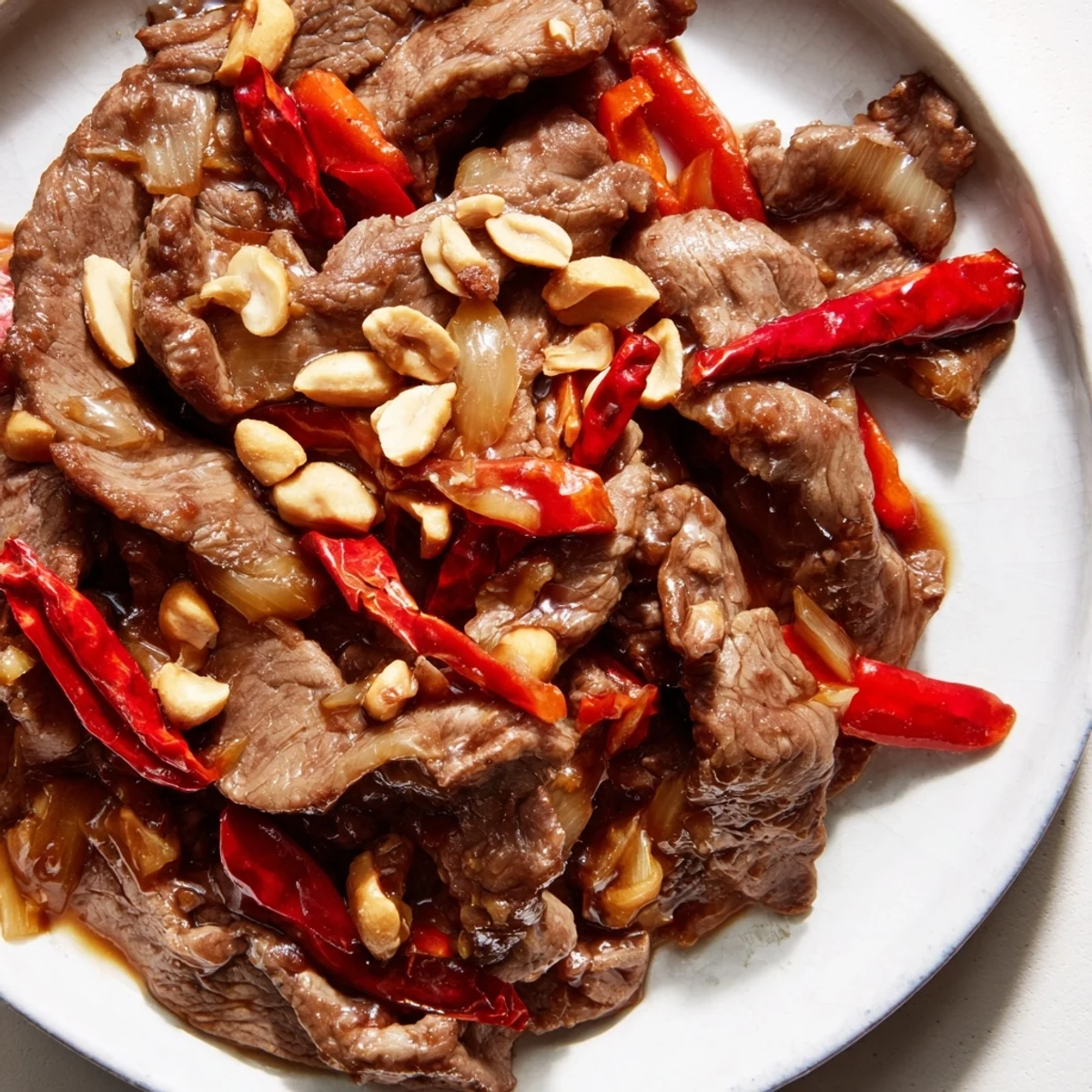 Sizzling Spicy Szechuan Beef with Peanuts paired with crisp bell peppers on a dinner plate.