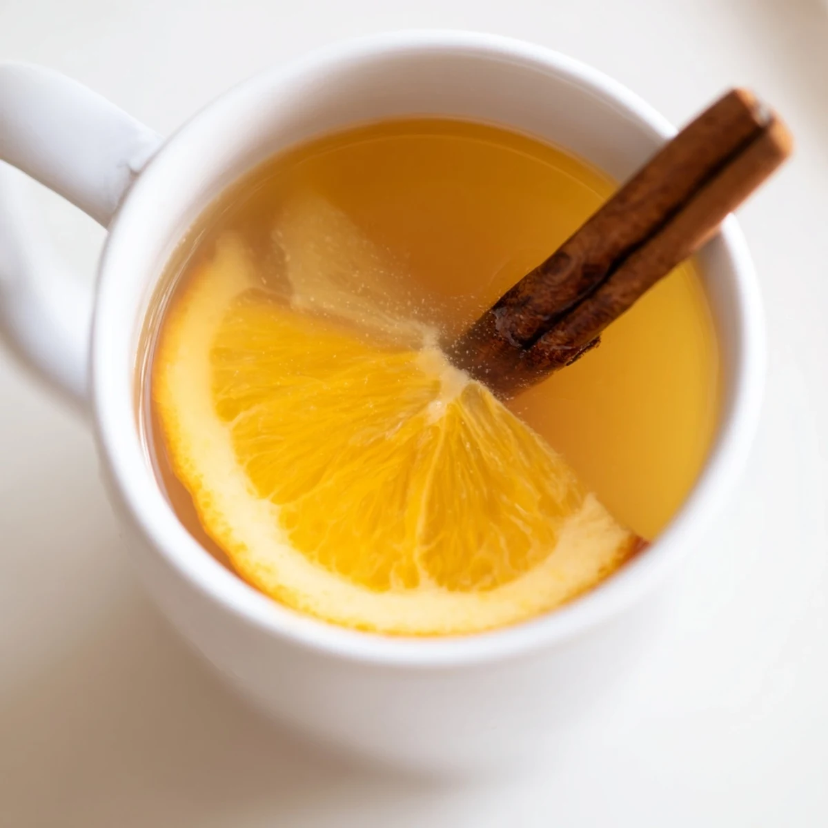 A ladle pours golden Spiced Hot Apple Juice with Cinnamon into a mug, paired with a holiday cookie on a wooden table.