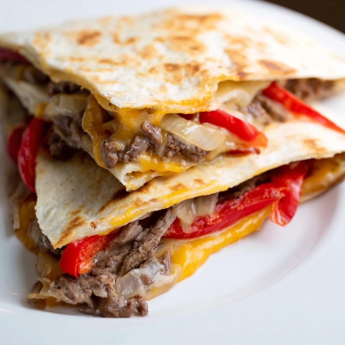 Freshly cooked Beef Quesadillas with salsa and guacamole, displaying melted cheese and savory beef inside golden-brown tortillas.