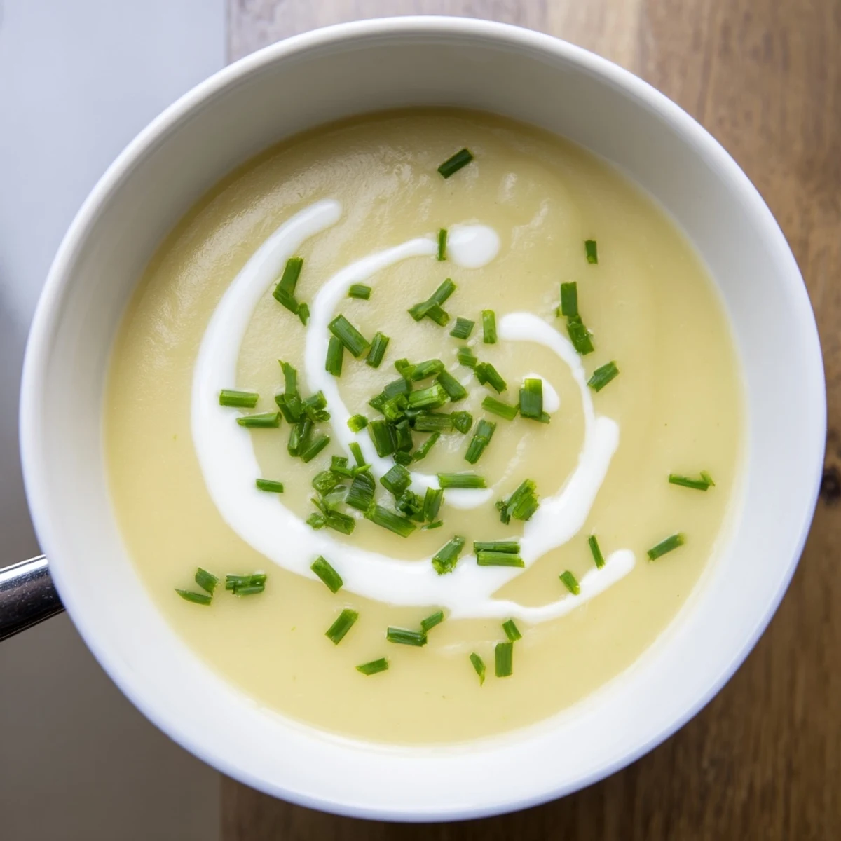 A warm bowl of Creamy Potato Leek Soup with Chives, served alongside crusty artisan bread for dipping.