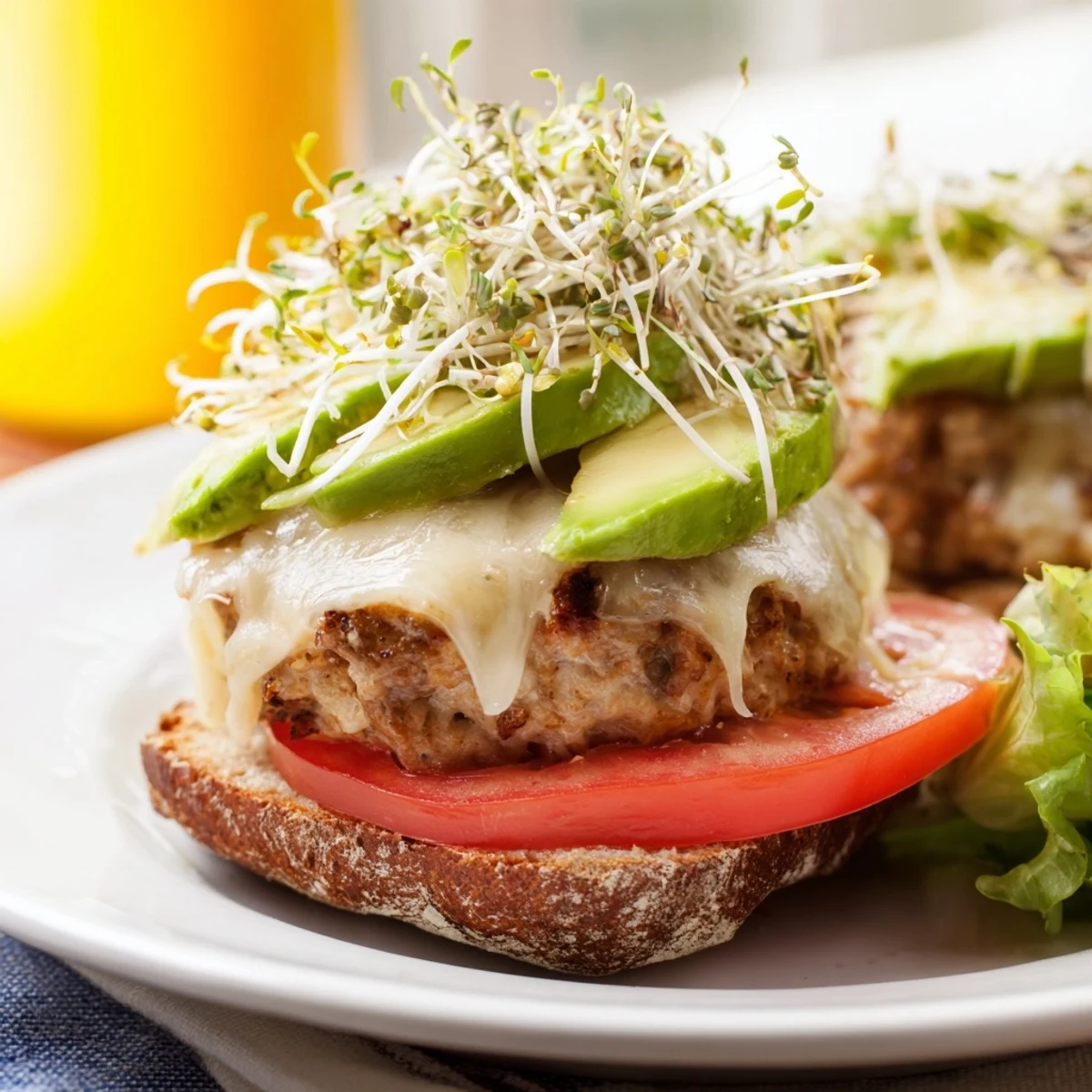 A juicy turkey burger topped with melted Swiss cheese, creamy avocado slices, and crunchy sprouts on a toasted bun.