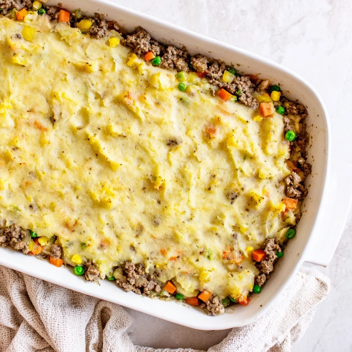 Golden-brown Beef Shepherds Pie with Cauliflower Mash rests in a white dish, a comforting low-carb main dish ready to serve.