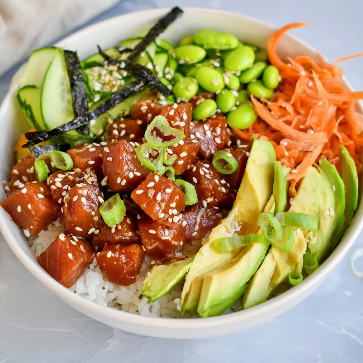 A close-up of a vibrant Spicy Tuna Poke Bowl with creamy avocado slices and fresh vegetables on fluffy rice.