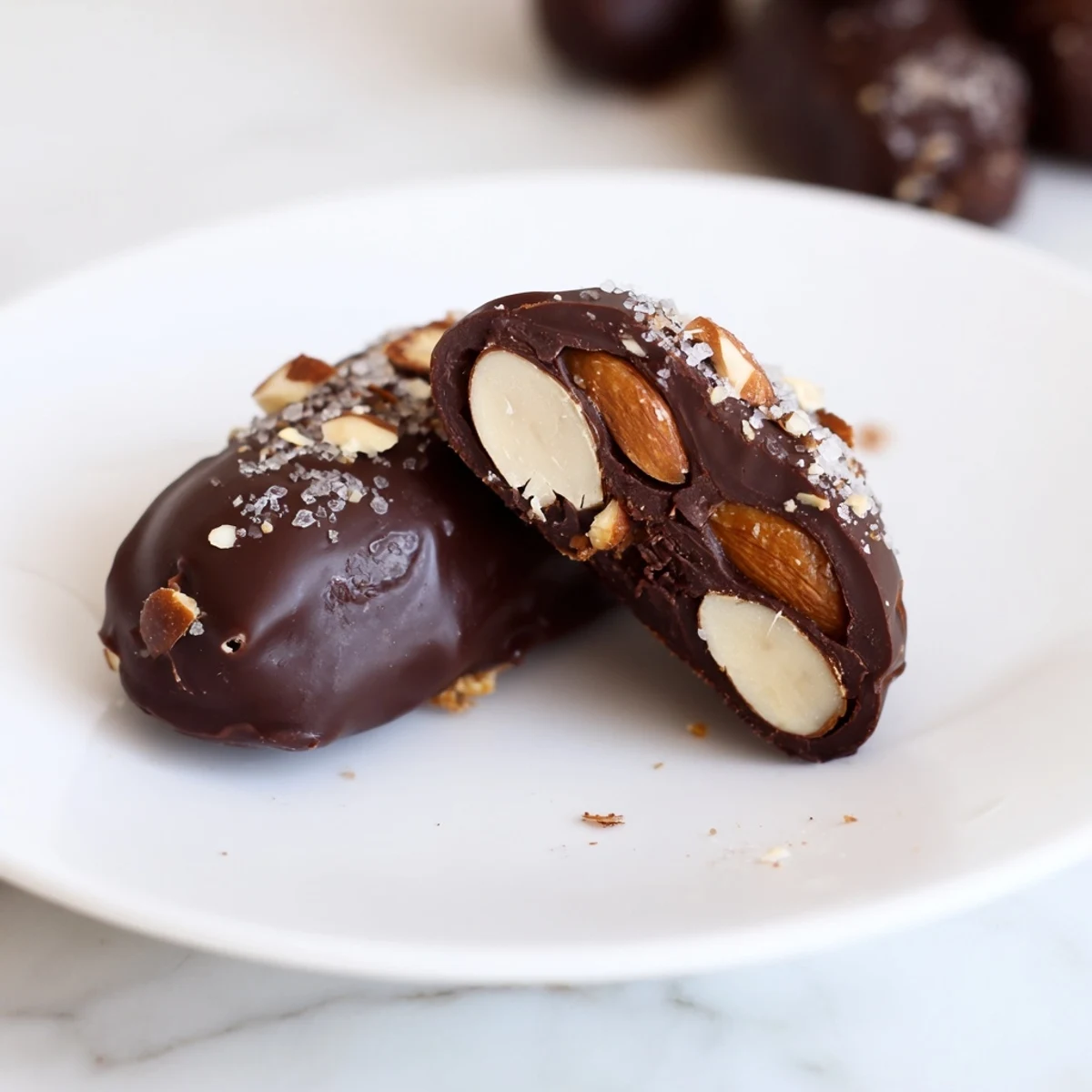 A close-up of Chocolate Covered Dates Stuffed with Almond Butter, showing the glossy dark chocolate shell and a drizzle of almond butter.