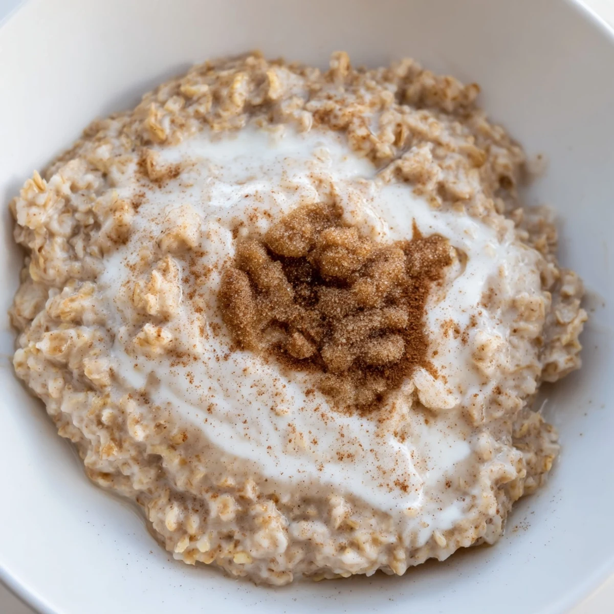Comforting Irish Oatmeal with Brown Sugar and Cream in a steaming bowl, ready for breakfast with a wooden spoon nearby.