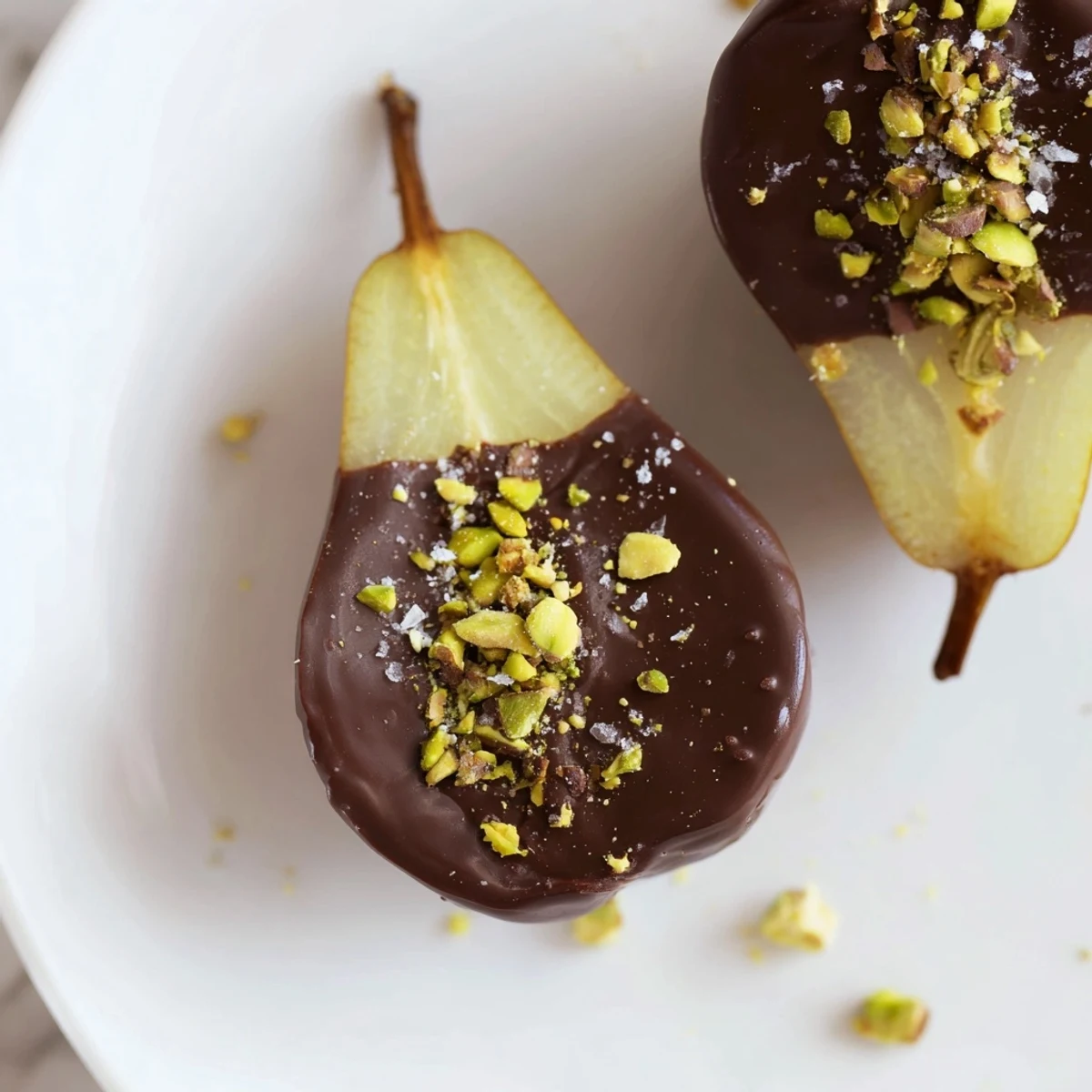 Glossy halves of ripe pears dipped in dark chocolate, finished with flaky sea salt for an elegant dessert.