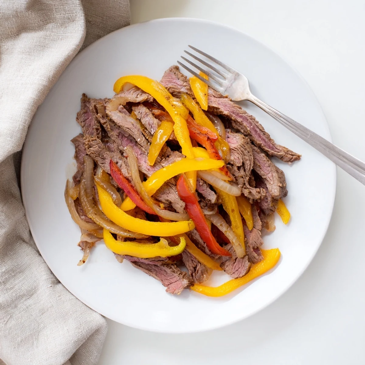 Sizzling Beef Fajitas with Peppers and Onions served in warm tortillas, garnished with fresh cilantro and lime wedges for a classic Tex-Mex dinner.  