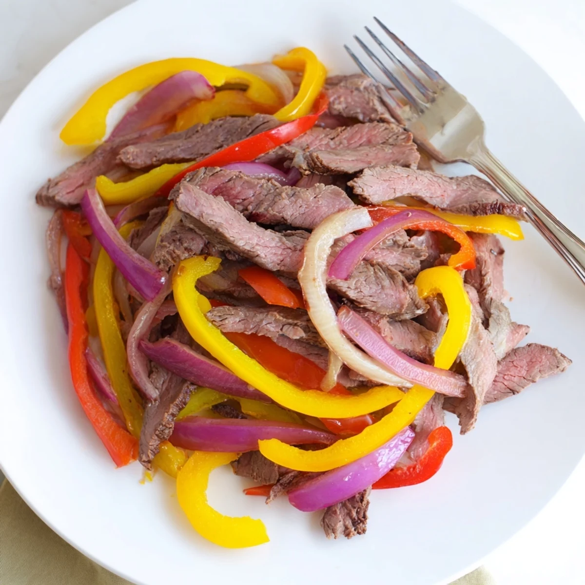 Beef Fajitas with Peppers and Onions plated with flour tortillas, lime, and toppings, showcasing a vibrant and appetizing weeknight meal.