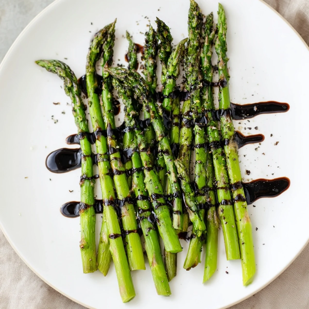 Close-up of tender roasted asparagus with balsamic glaze, garnished with a sprig of herbs, perfect for a gluten-free and vegan-friendly meal.