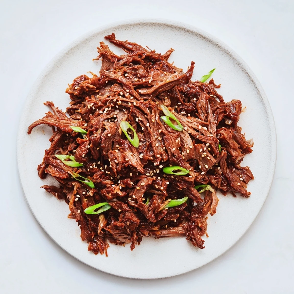 A fork lifts tender shredded slow cooker Korean beef, ready to be served over fluffy white rice.