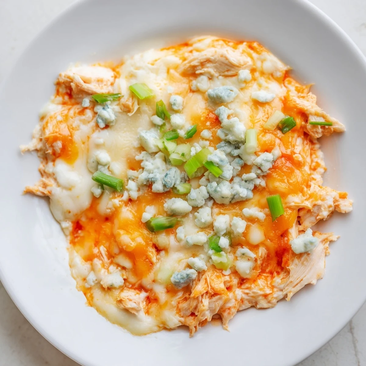 Freshly baked Keto Buffalo Chicken Dip bubbling with melted cheese and shredded chicken, served with celery sticks on a rustic wooden table.