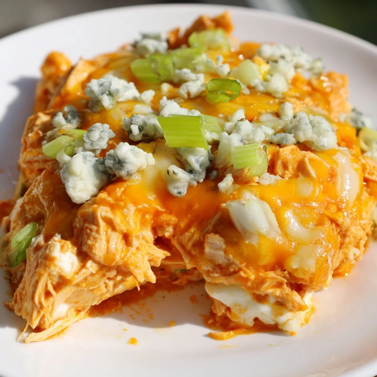 Close-up of Keto Buffalo Chicken Dip with tender shredded chicken, gooey mozzarella, and a golden-brown crust on a marble countertop.
