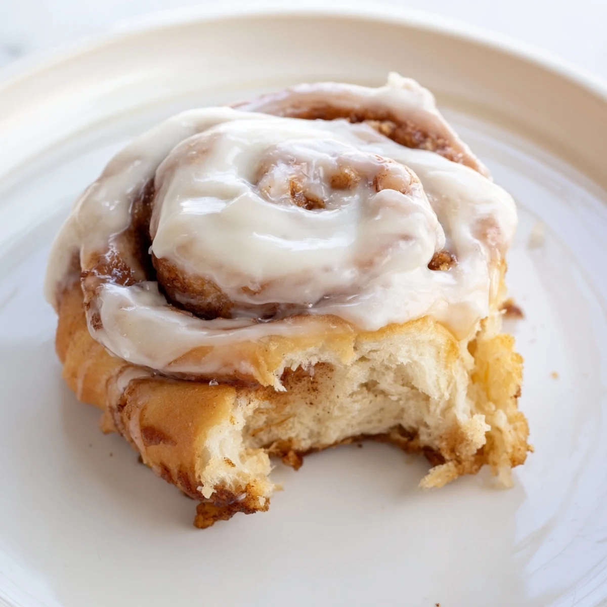 Freshly baked Keto Cinnamon Buns with a swirl of cinnamon filling and creamy icing on a marble counter.