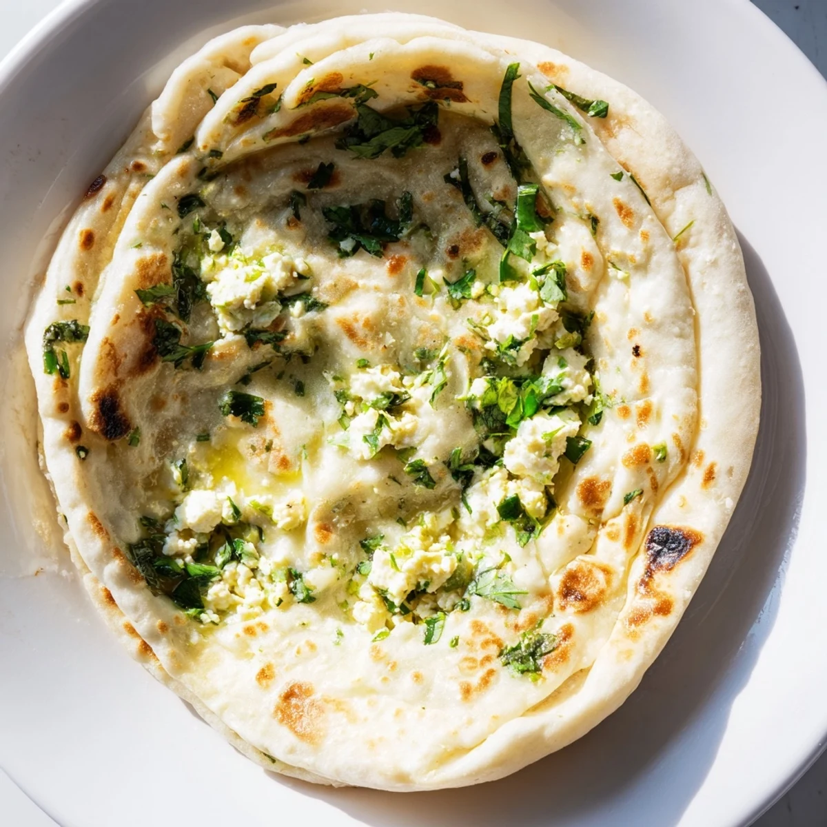 Warm Cottage Cheese Garlic Naan stuffed with creamy cottage cheese, brushed with garlic butter, and garnished with cilantro on a wooden serving board.
