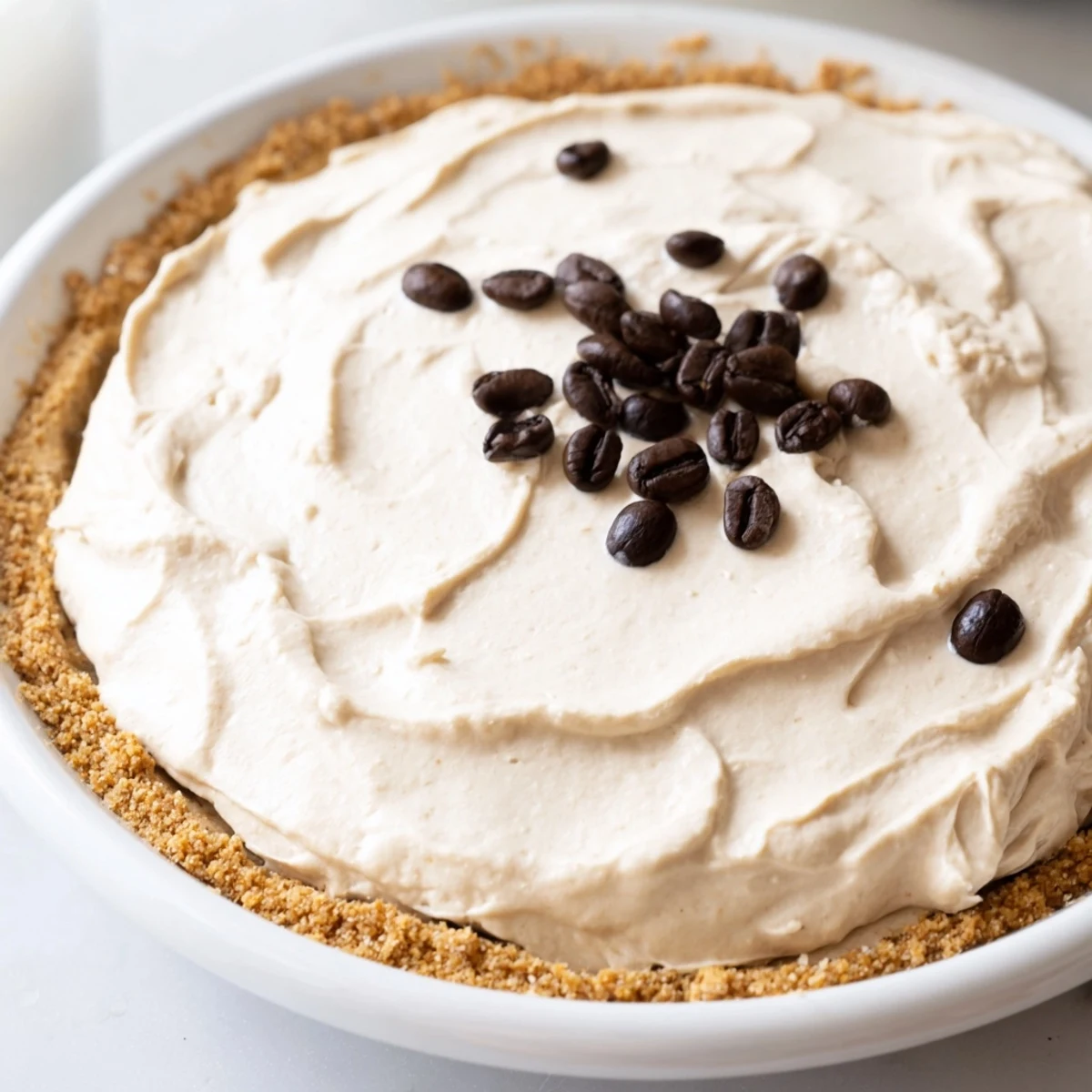 Smooth and creamy keto dessert with almond flour crust and whipped topping, served on a rustic wooden table. 