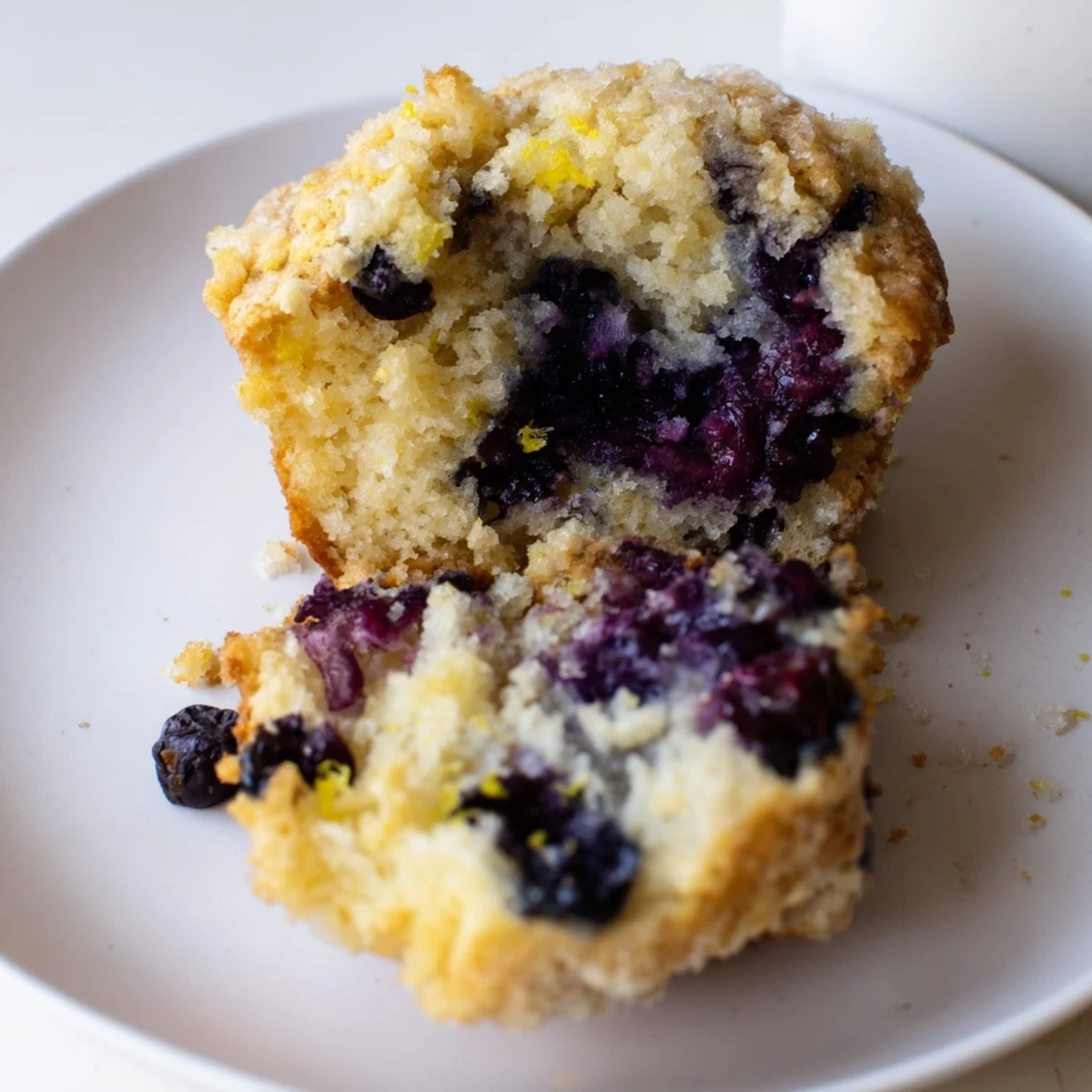 Warm Sourdough Blueberry Muffins with a crumbly turbinado sugar topping, served on a rustic plate for an afternoon snack.