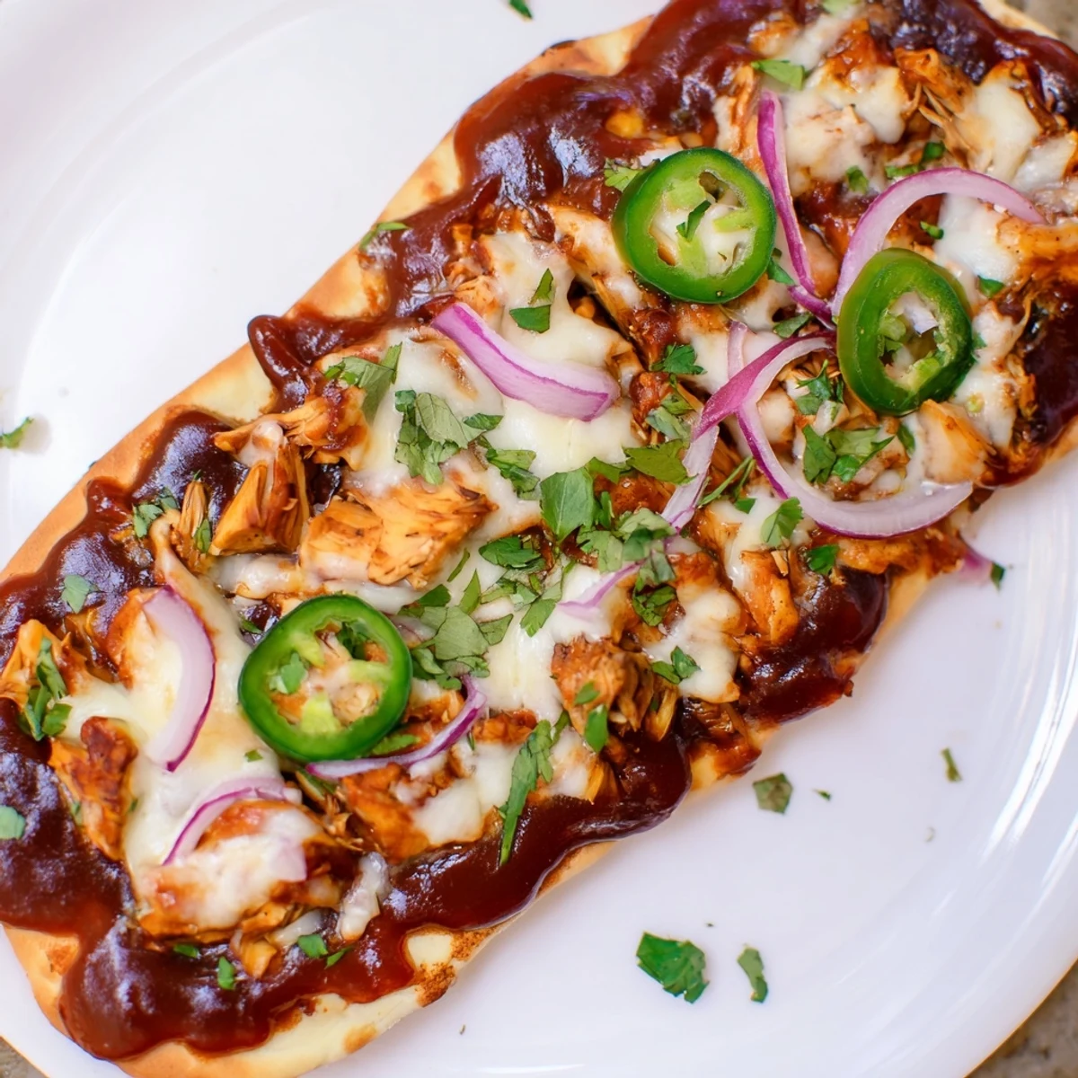 BBQ Chicken Flatbread fresh from the oven, bubbling with cheese and drizzled with tangy sauce, ready to serve for dinner.