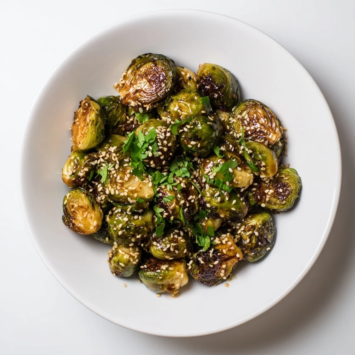Golden Honey Sriracha Brussels sprouts served warm in a ceramic bowl, ideal for a vegetarian dinner side dish.