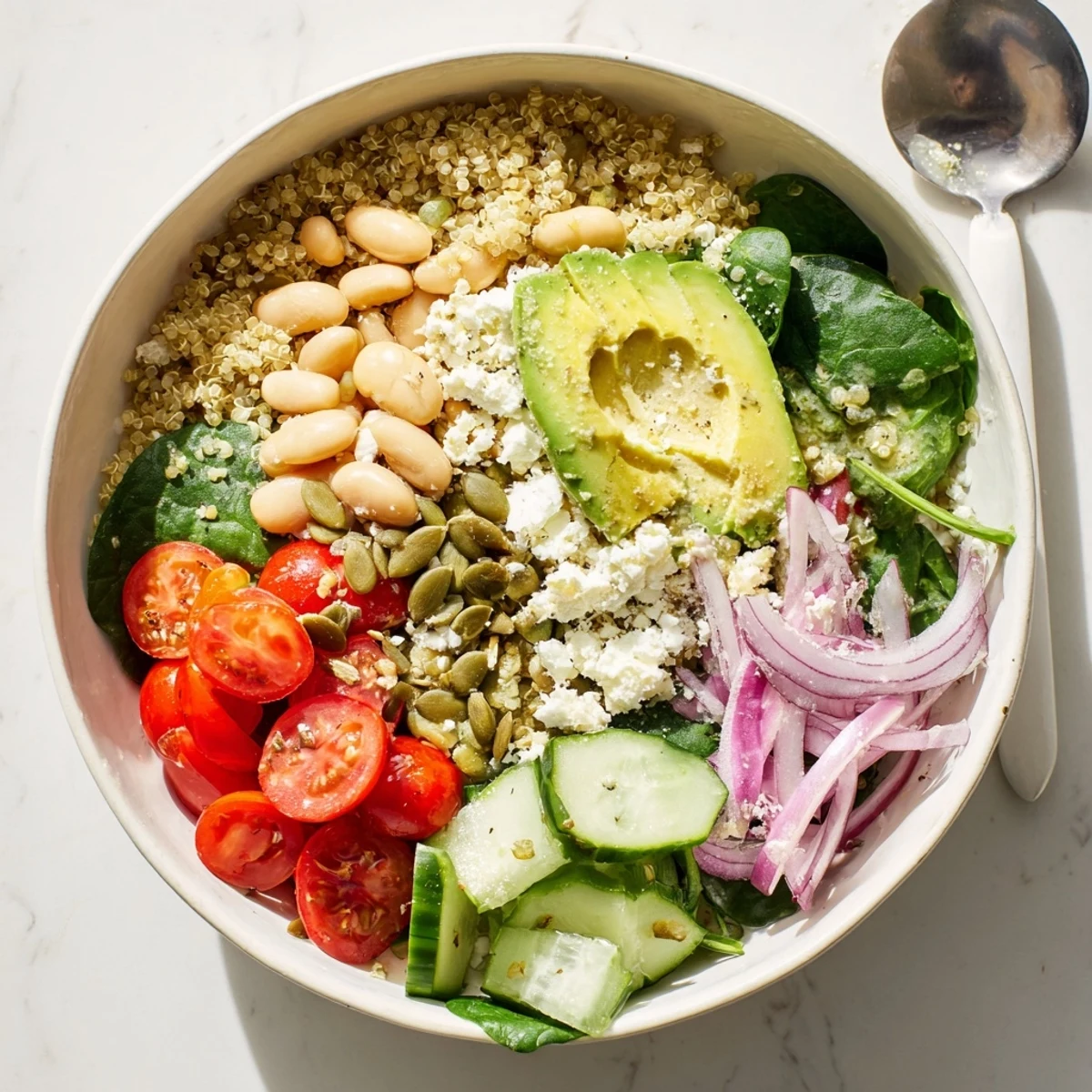 A close-up of the Spinach & White Bean Ultimate Protein Power Bowl with creamy avocado and lemon-tahini dressing.