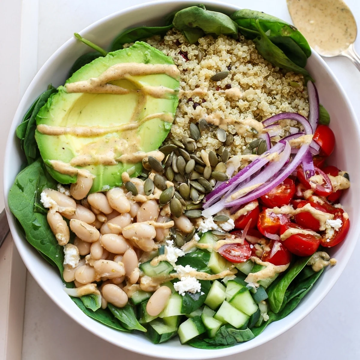 Colorful Spinach & White Bean Ultimate Protein Power Bowl with cucumber and red onion, ready for a healthy dinner.