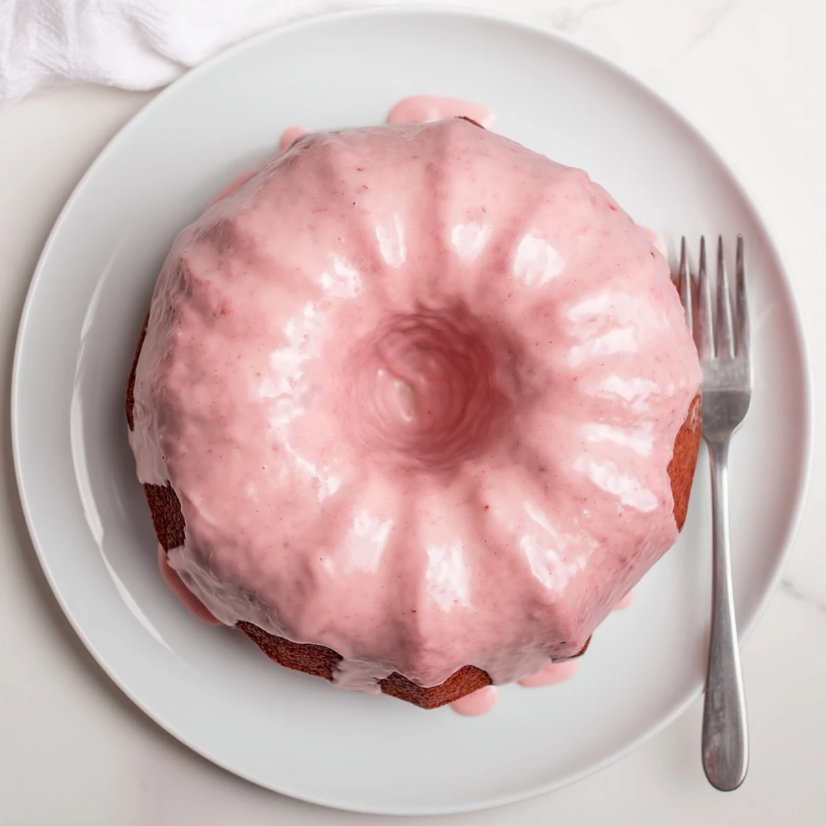 A golden pound cake infused with strawberry milk flavor, topped with a vibrant pink strawberry glaze.  