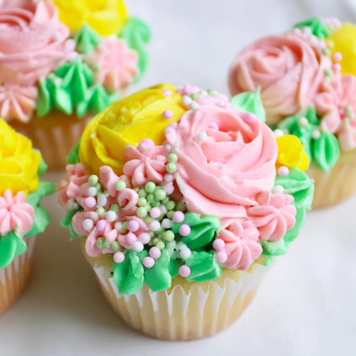 A close-up view of Baby In Bloom Cupcakes topped with vivid floral buttercream and edible violet petals.