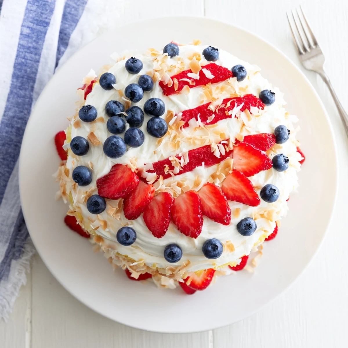 Sliced cake reveals tender crumb with pineapple and coconut, garnished with strawberries and blueberries.