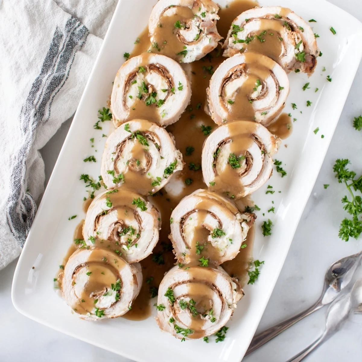 Golden-brown, juicy Flavor-Packed Turkey Roll-Ups with Stuffing served hot with creamy gravy drizzled on top.  