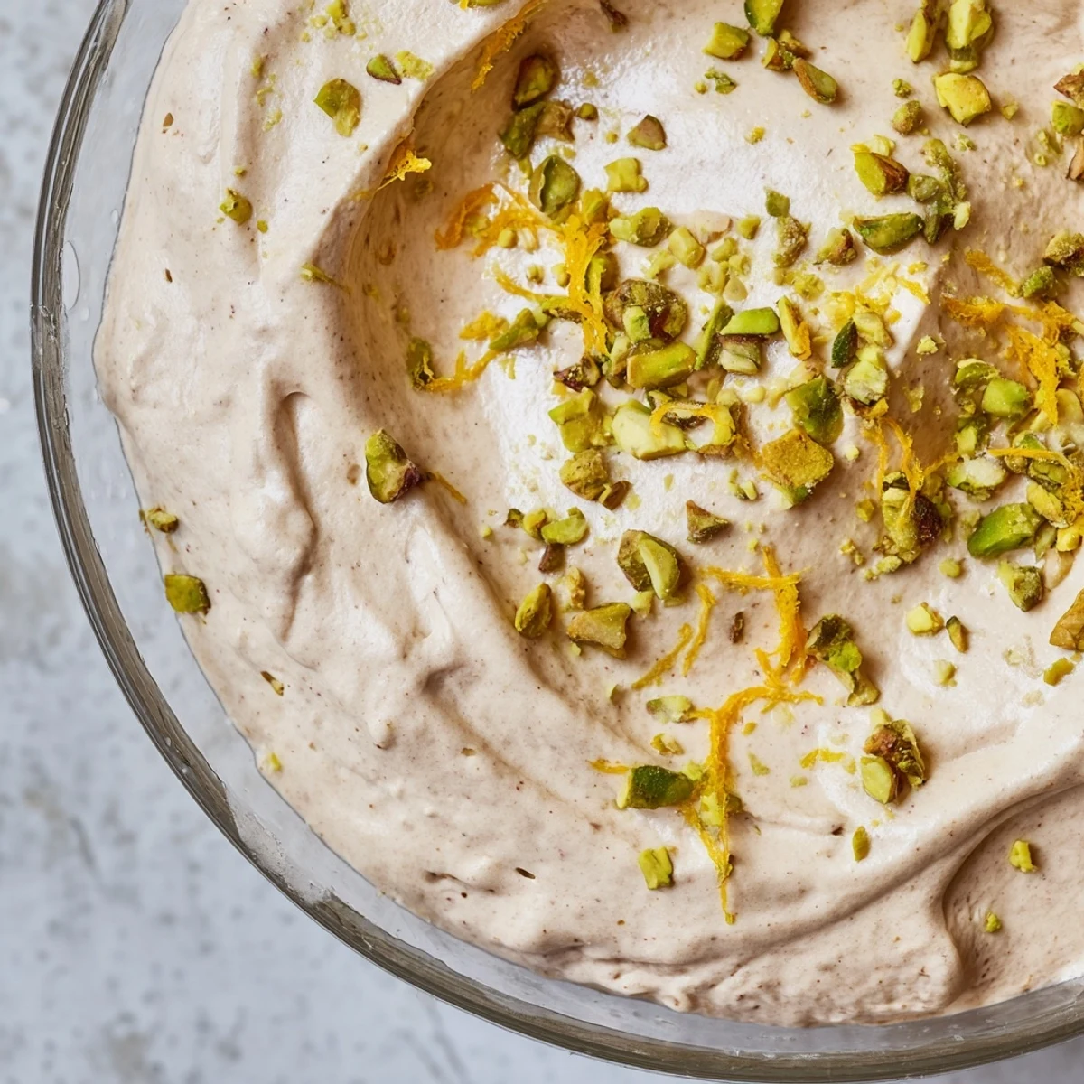 Creamy Lebanese date orange blossom mousse topped with crushed pistachios and fresh orange zest in a glass bowl