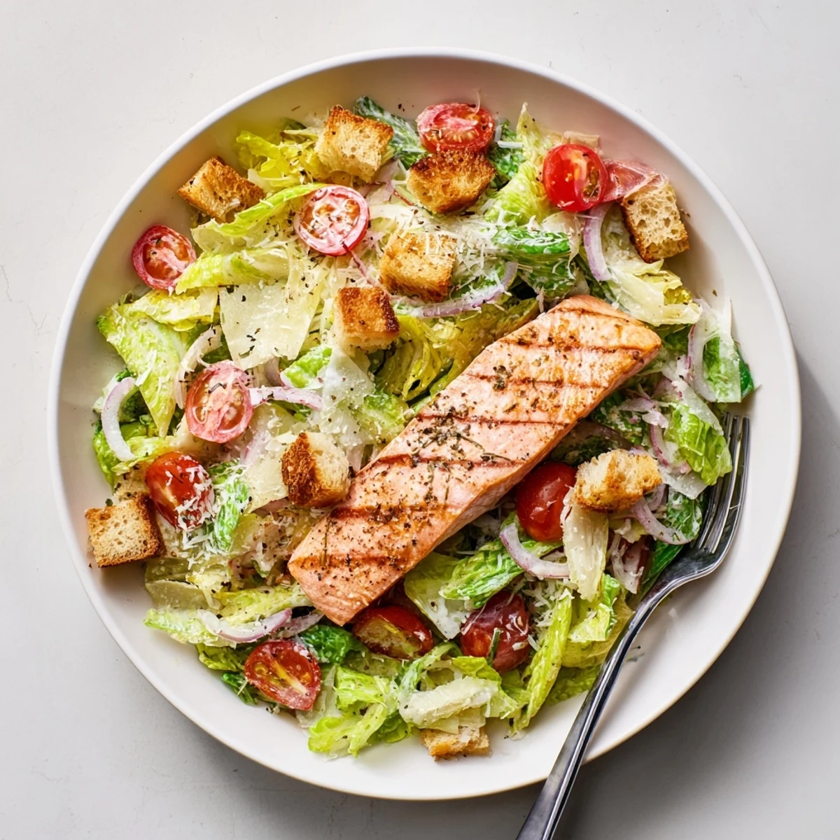 Flaky grilled salmon served over romaine lettuce with rich Caesar dressing, red onion, and golden croutons