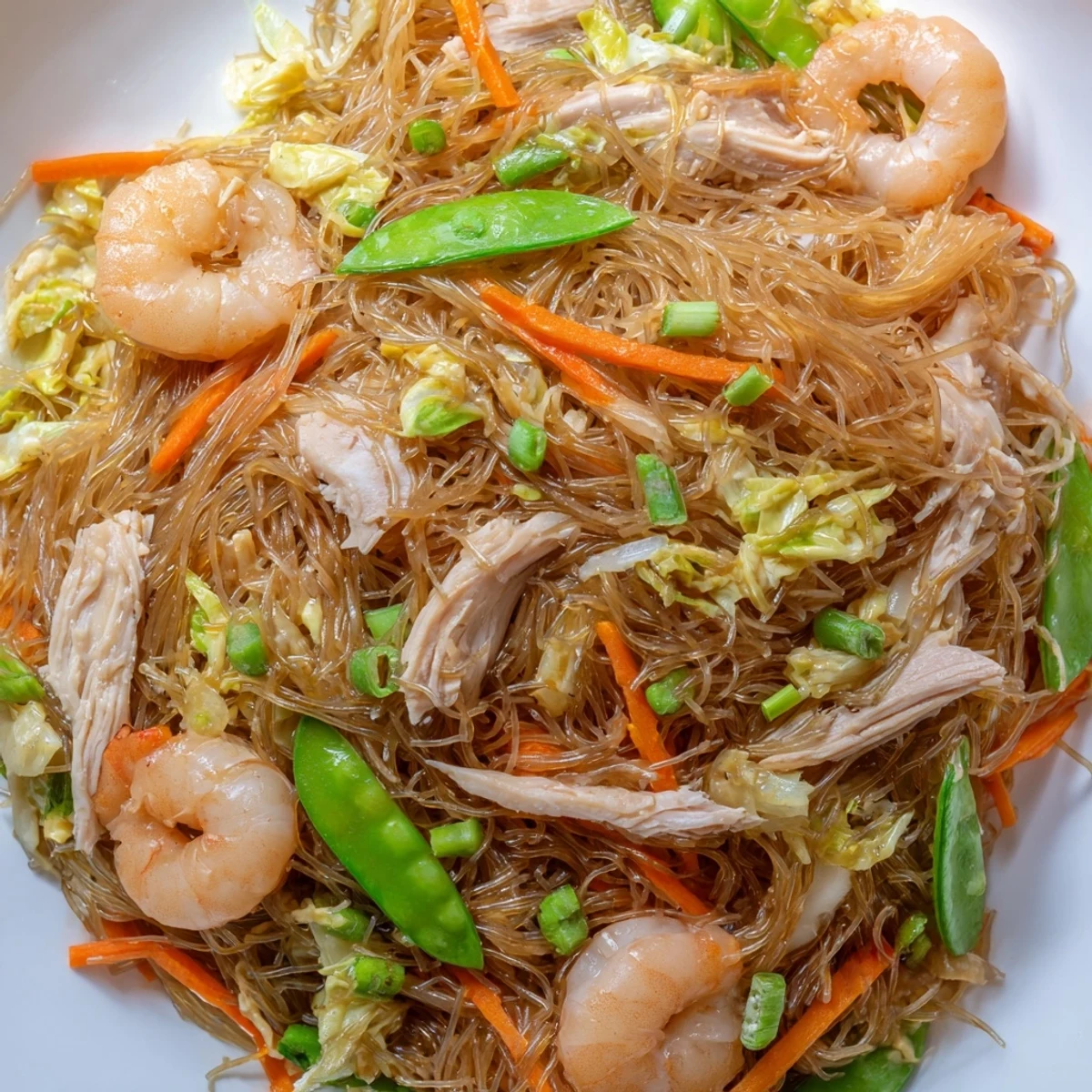 Hearty Filipino Pancit Bihon featuring tender rice noodles with protein and crisp veggies in rich sauce.