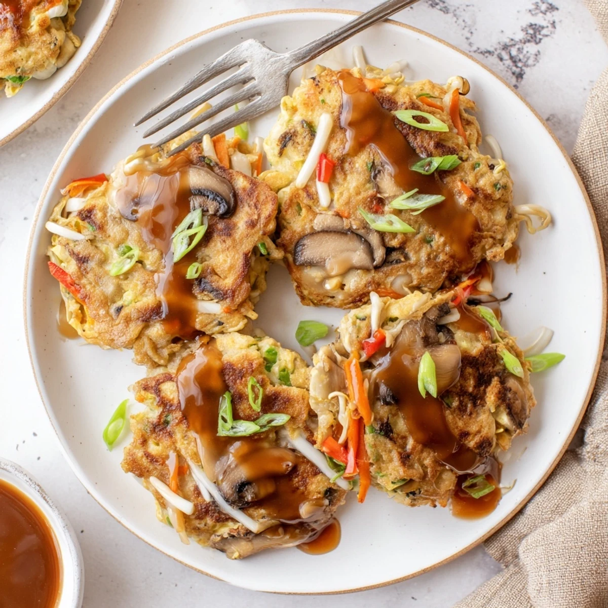 Chinese American Egg Foo Young served hot with drizzled sauce and fresh green onions