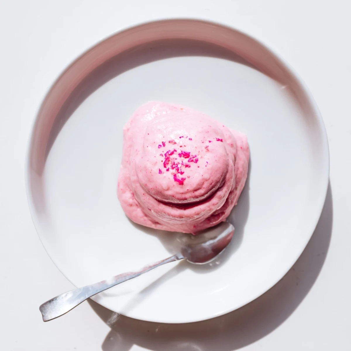 Silky homemade pink lemon curd being drizzled over vanilla cake layers