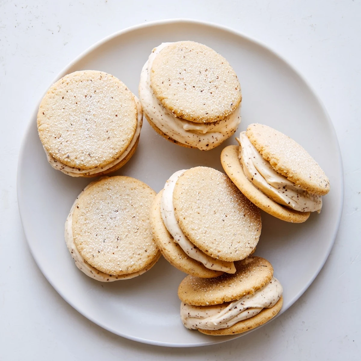 Plate of homemade chai shortbread cookie sandwiches dusted with powdered sugar ready for tea time