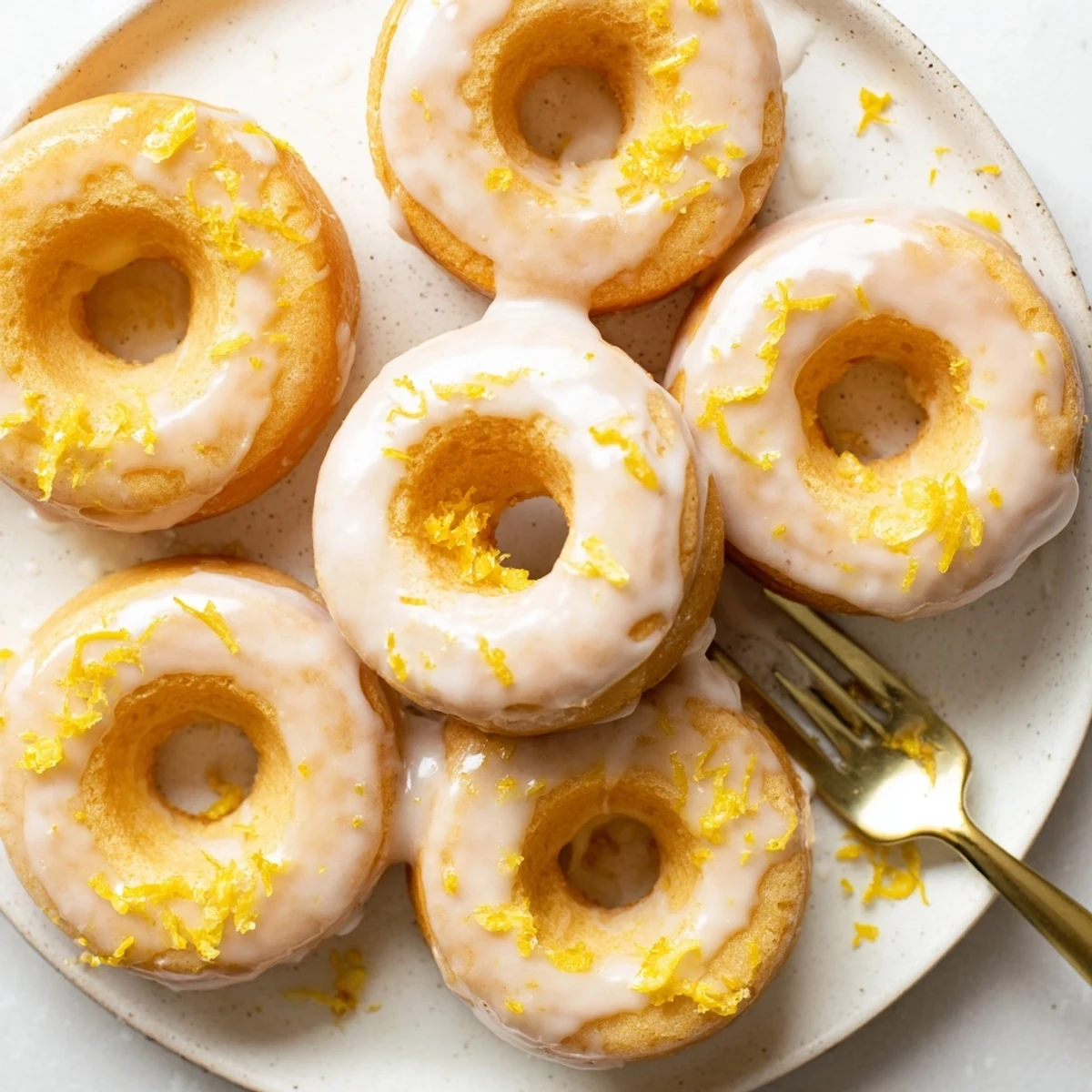 Soft pillowy lemon mochi donuts arranged on a wire rack after dipping