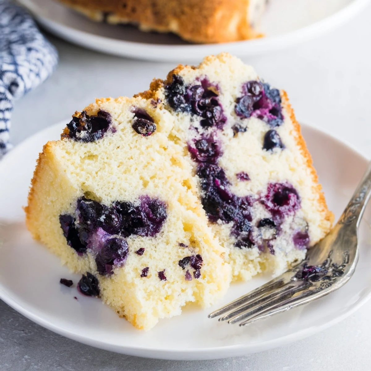 Fluffy blueberry chiffon cake with fresh berries baked into golden airy layers on a white serving plate