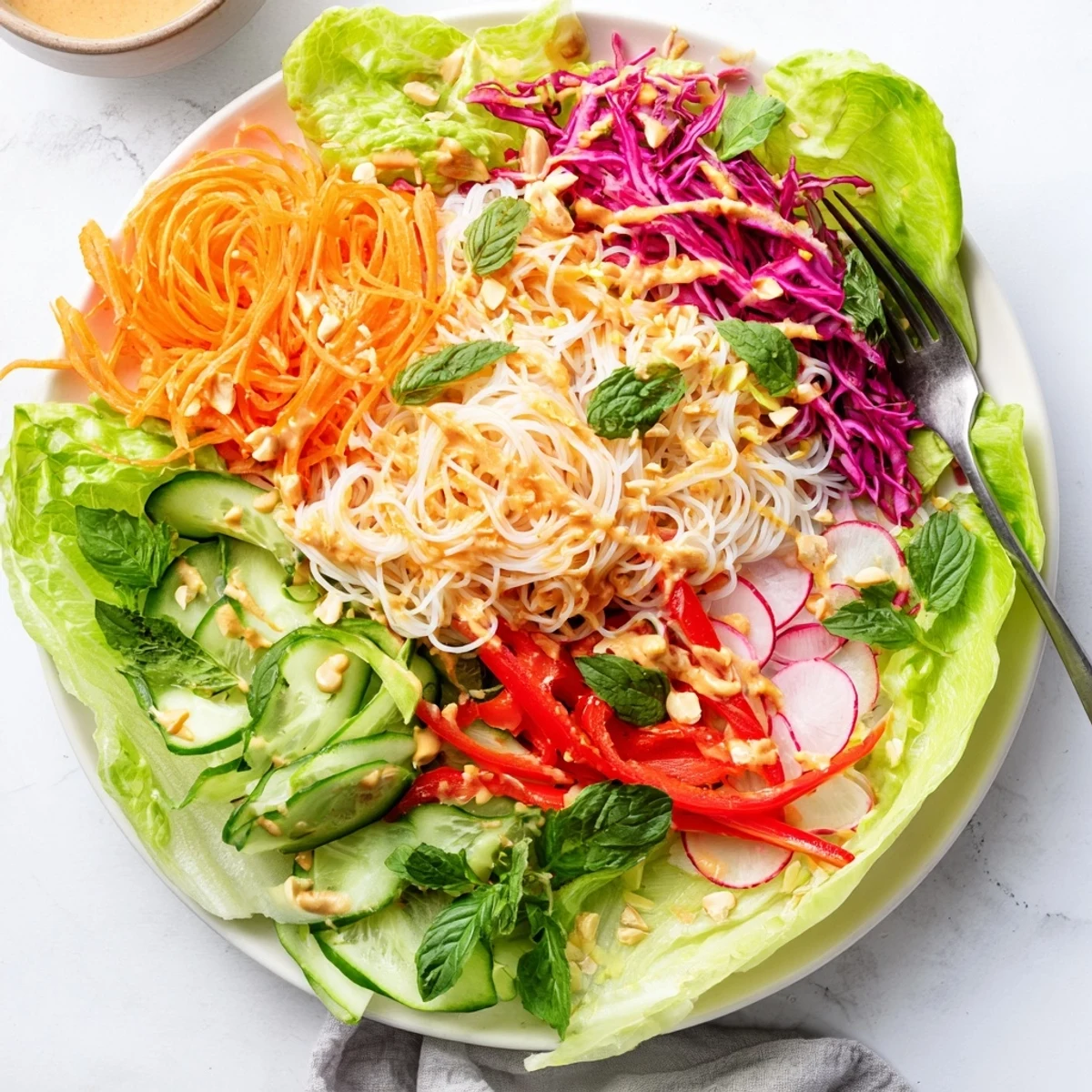 Colorful spring roll salad with peanut dressing featuring crisp julienned vegetables and rice noodles