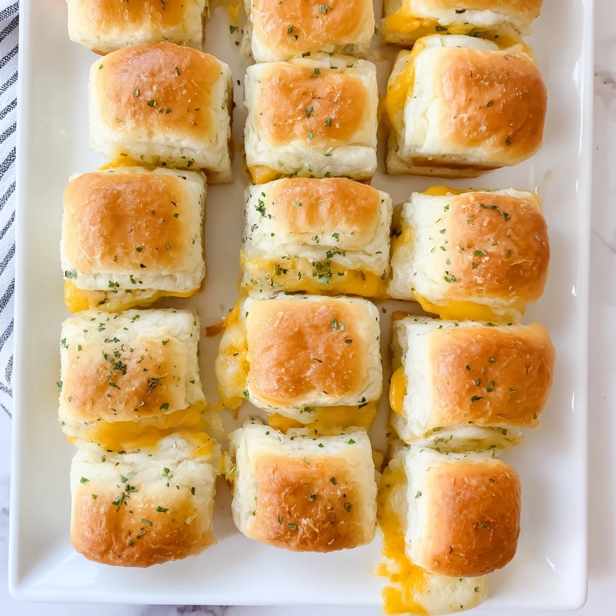Warm Hawaiian roll sliders stuffed with gooey melted cheese and brushed with garlic butter