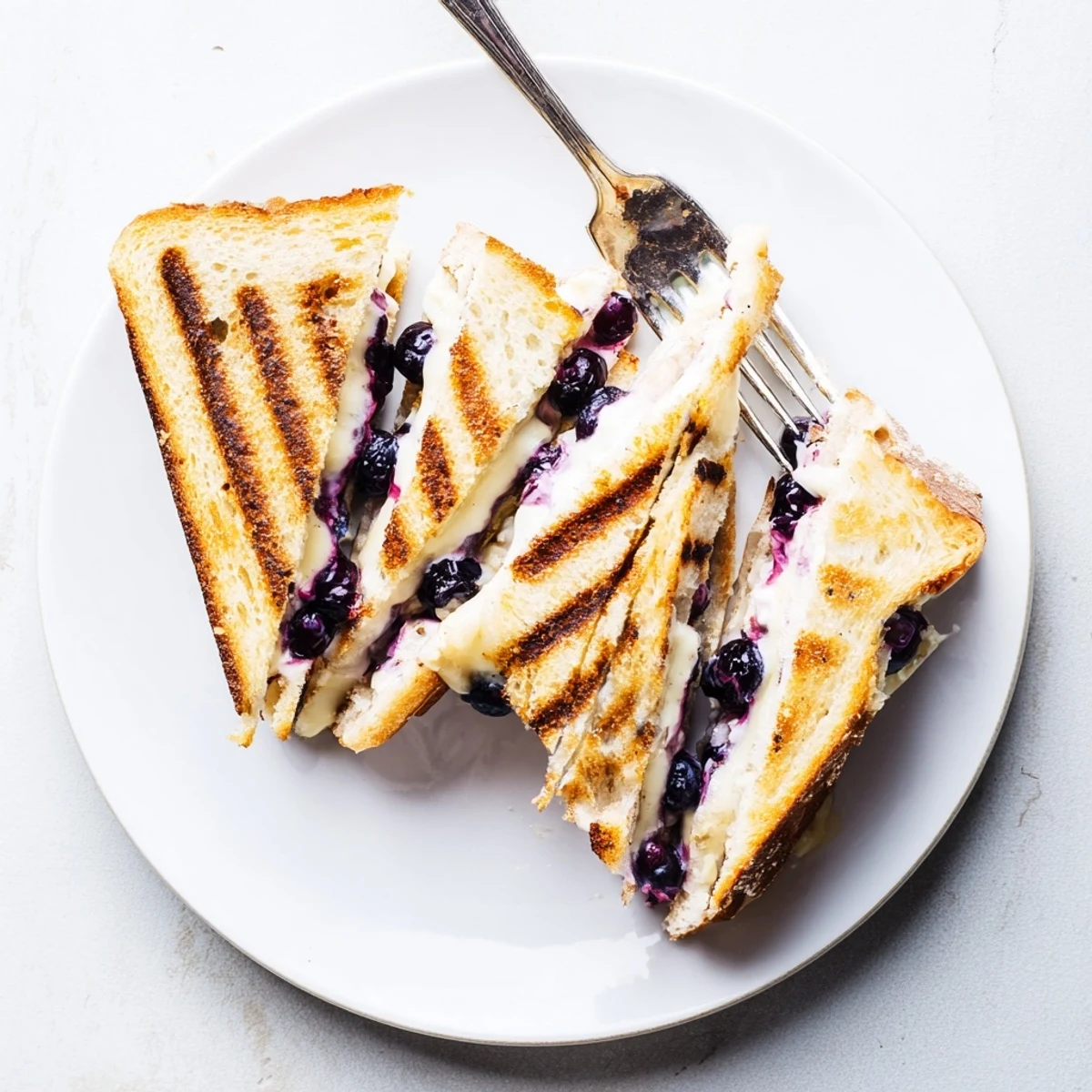Golden grilled cheese sandwich stuffed with melted cheddar and bursting fresh blueberries