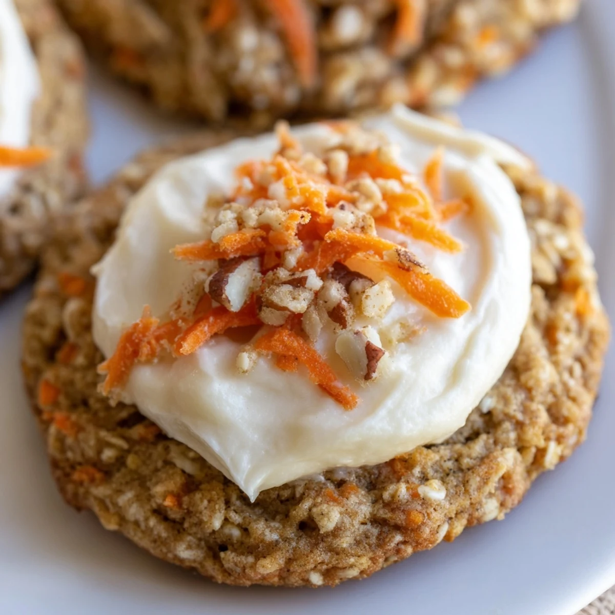 Soft carrot cake cookies topped with swirls of creamy white frosting and chopped walnuts