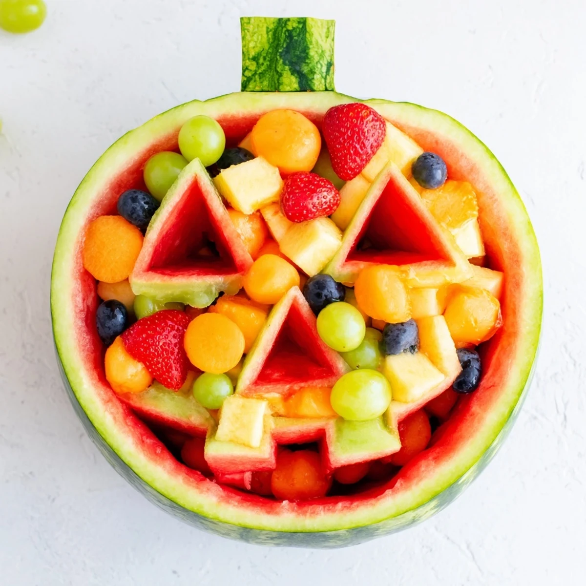 Whimsical Halloween watermelon Jack O Lantern fruit salad displaying vibrant mixed seasonal fruits