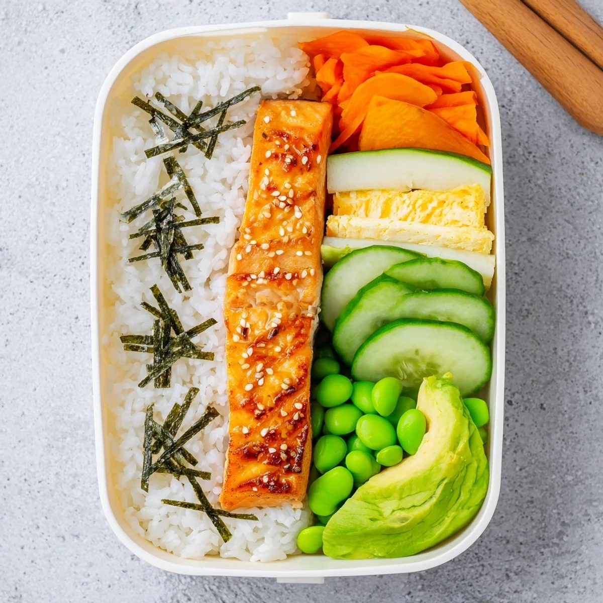 Healthy Japanese breakfast bento box with grilled salmon, fluffy rice, and colorful pickled vegetables arranged in compartments