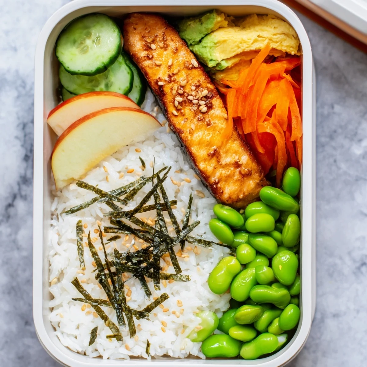Nourishing bento breakfast with seasoned fish, pickled cucumber carrots, and sliced avocado for a balanced morning meal