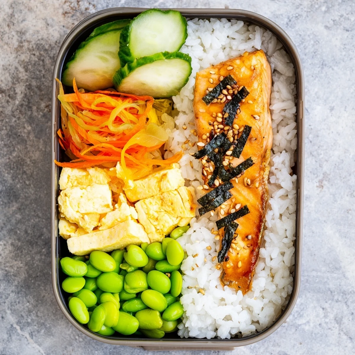 Traditional Japanese breakfast bento featuring flaky fish, steamed rice, and fresh fruit in a divided container