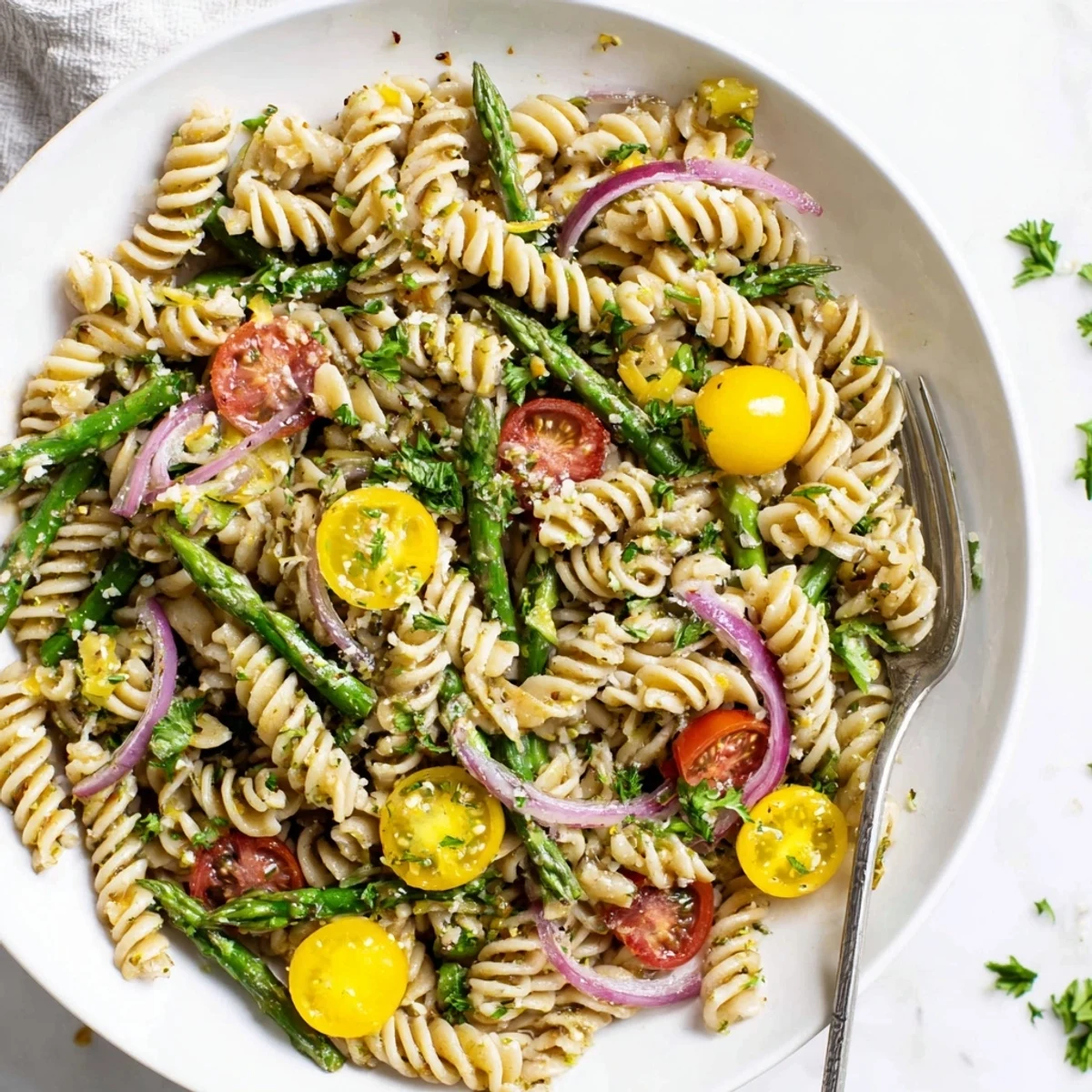 Colorful bowl of lemon asparagus pasta salad garnished with fresh parsley and grated parmesan cheese