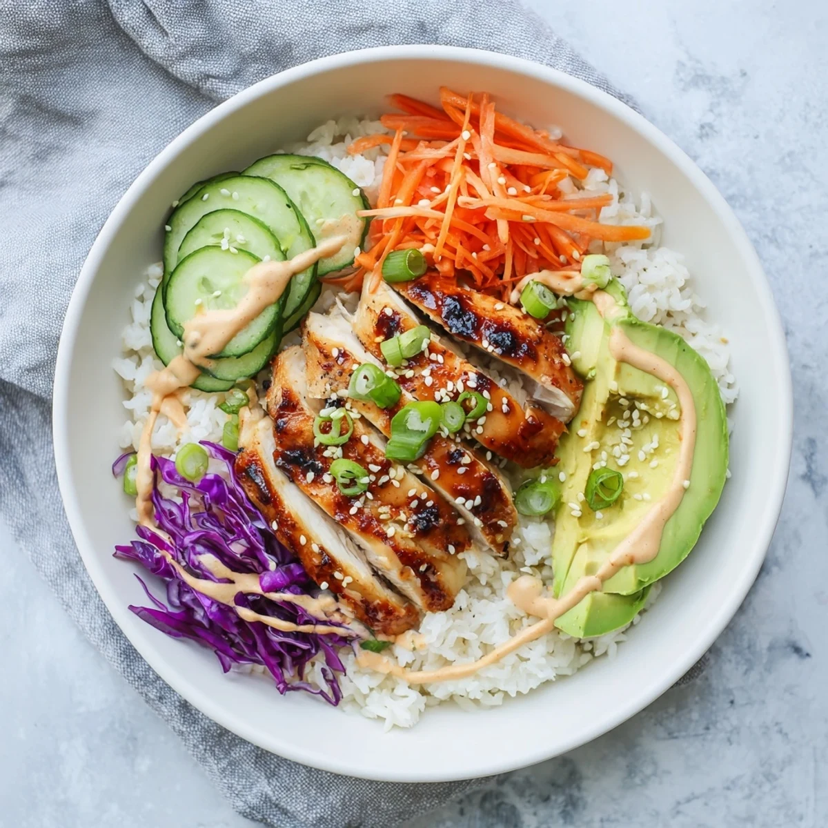 Vibrant Korean BBQ chicken bowl featuring tender marinated meat over rice with crisp carrots, cucumber, purple cabbage, and creamy chili mayo.