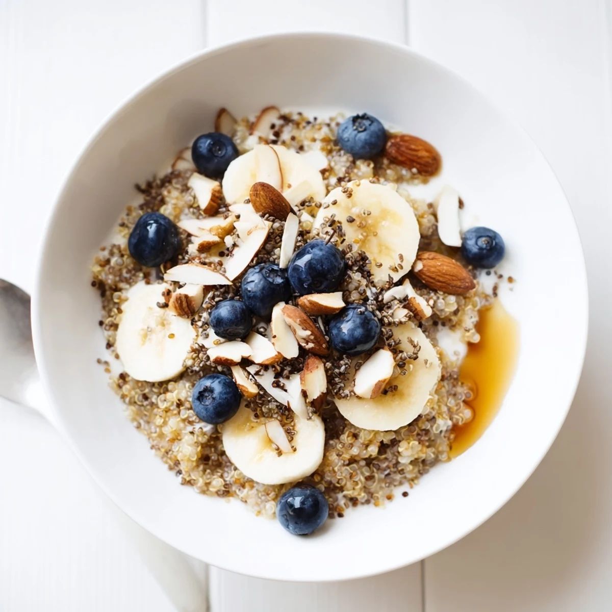 Warm blueberry quinoa breakfast bowl served with creamy yogurt and sweet maple syrup drizzle